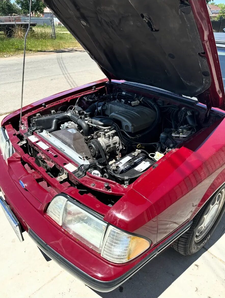 Classic red Ford Mustang with the hood up in the shop
